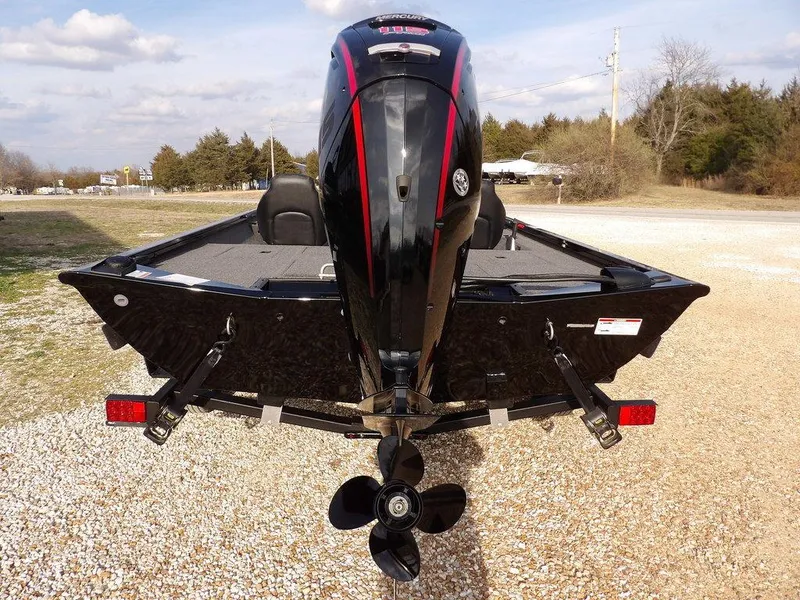 Slide: The Image of 2025 Crestliner XFC 189 boat, rear view with outboard motor, parked on gravel. - 6