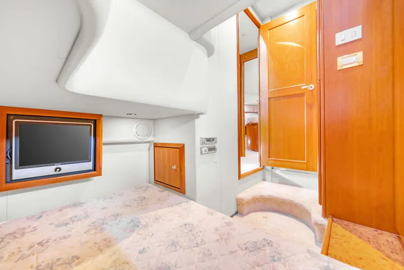 Slide: The Image of 2007 Silverton 45 Convertible yacht interior with TV, wooden cabinets, and cozy bedding. - 20