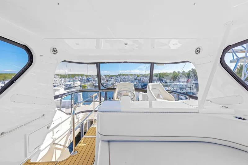 Slide: The Image of 2007 Silverton 45 Convertible yacht interior with marina view, featuring white seating and helm. - 27