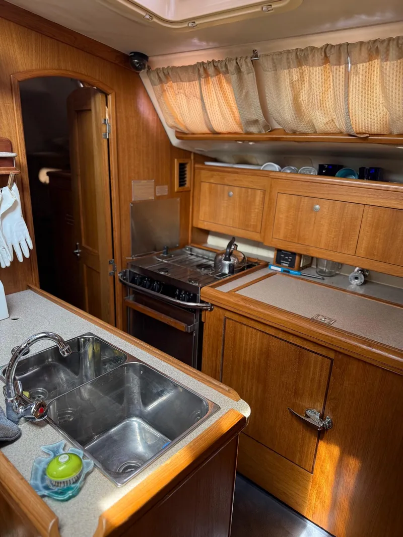 Slide: The Image of 2001 Hunter 460 yacht kitchen with wooden cabinets, dual sink, and stove. - 13