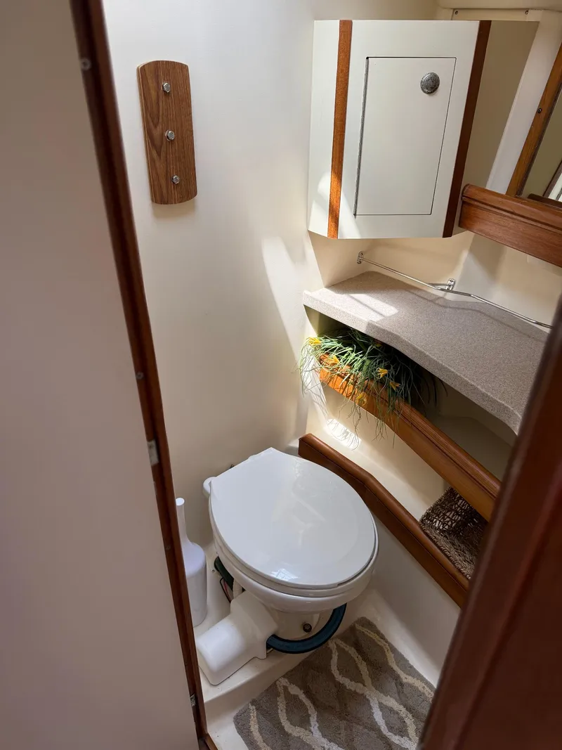 Slide: The Image of Compact bathroom in a 2001 Hunter 460 yacht, featuring a toilet and storage cabinet. - 21