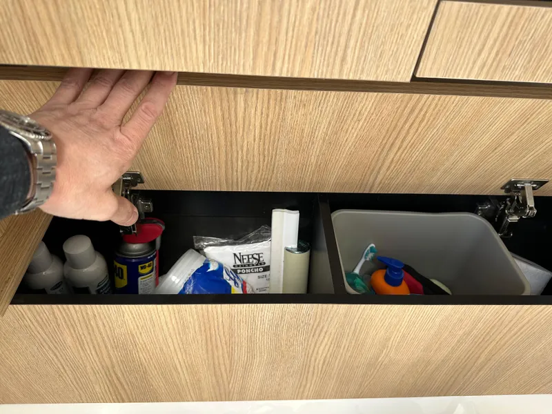 Slide: The Image of Hand opening wooden cabinet with cleaning supplies on a 2014 Robalo R227 Dual Console boat. - 38