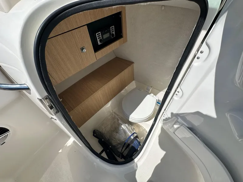 Slide: The Image of 2014 Robalo R227 Dual Console boat interior with compact bathroom and storage. - 7