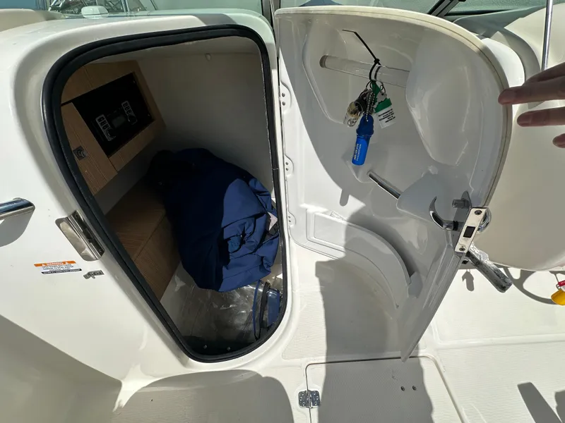 Slide: The Image of 2014 Robalo R227 Dual Console storage compartment with keys and blue jacket inside. - 8