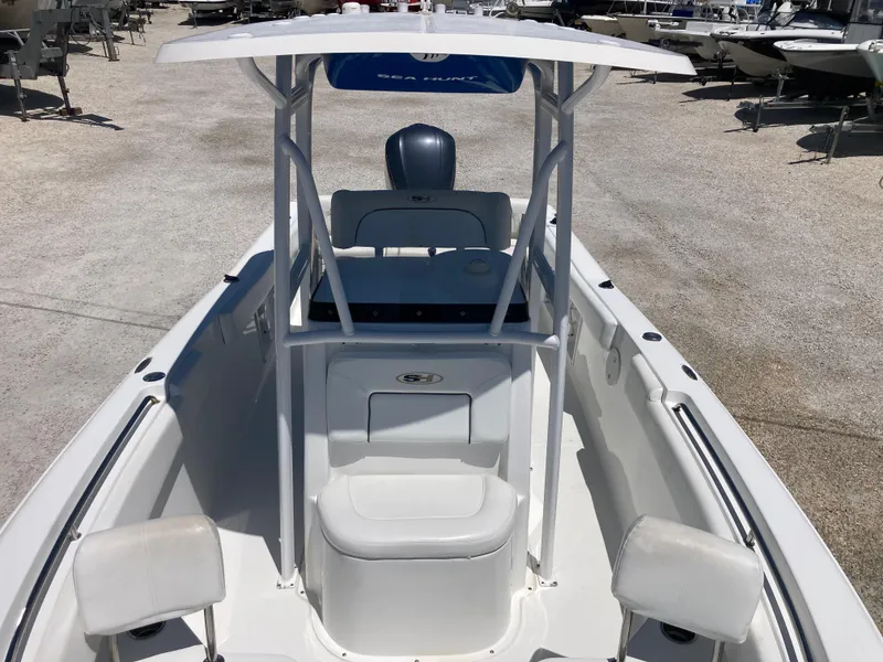 Slide: The Image of 2014 Sea Hunt 234 Ultra boat with T-top and seating, docked outdoors. - 11