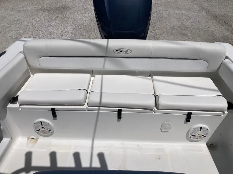 Slide: The Image of 2014 Sea Hunt 234 Ultra boat seating area with white cushions and built-in speakers. - 17