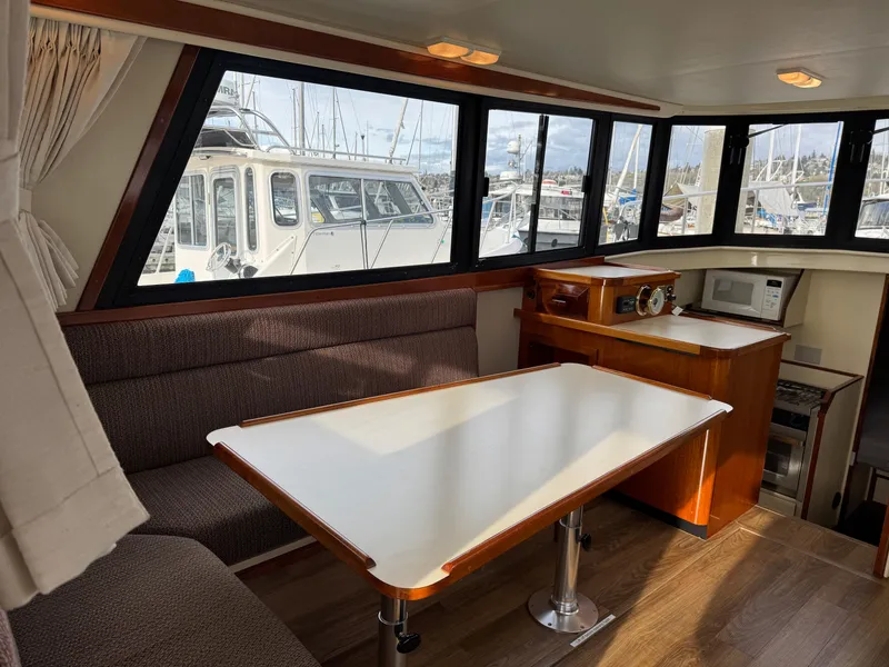 Slide: The Image of Interior of a 2003 Camano Troll boat with dining area and large windows. - 10