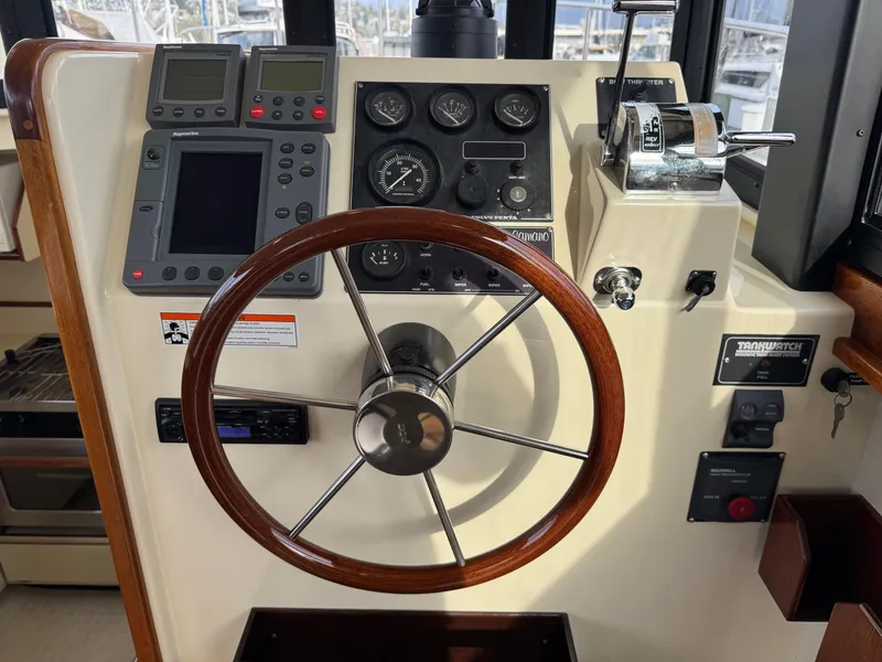 Slide: The Image of 2003 Camano Troll helm with wooden steering wheel, navigation instruments, and throttle controls. - 12