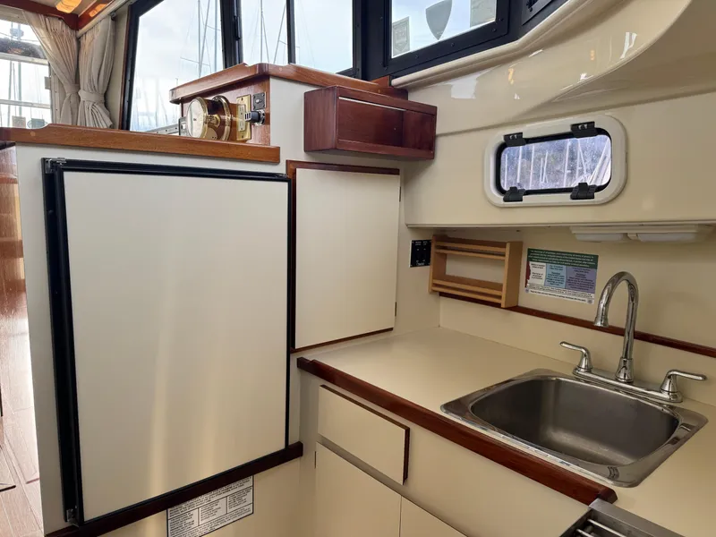 Slide: The Image of 2003 Camano Troll boat kitchen with sink, fridge, and wooden accents. - 16