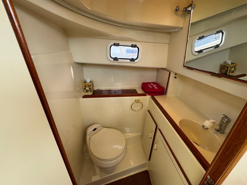 Slide: The Image of 2003 Camano Troll boat bathroom with toilet, sink, mirror, and porthole window. - 20