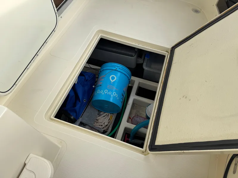 Slide: The Image of Storage compartment on a 2003 Camano Troll boat with a blue bucket and supplies. - 34