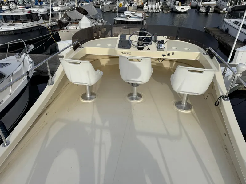 Slide: The Image of 2003 Camano Troll boat helm with three white seats, docked in a marina. - 6