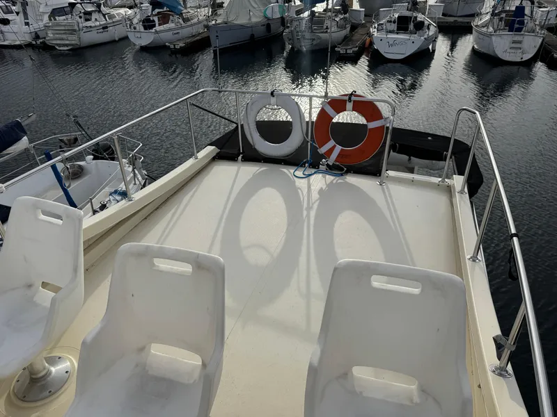 Slide: The Image of 2003 Camano Troll boat deck with chairs and life rings, docked in a marina. - 9