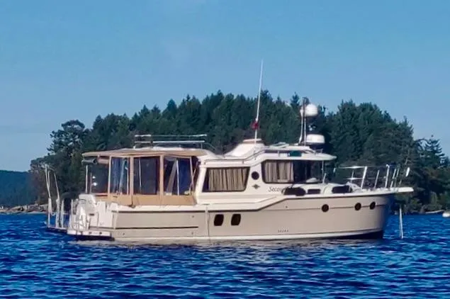 Slide: The Image of 2021 Ranger Tugs R-29 S boat on a serene lake with forested background. - 0