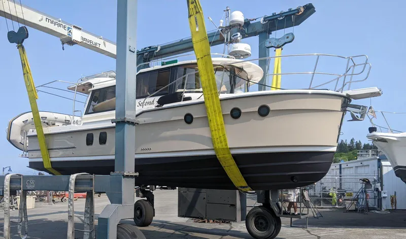 Slide: The Image of 2021 Ranger Tugs R-29 S boat in dry dock, supported by yellow straps. - 1