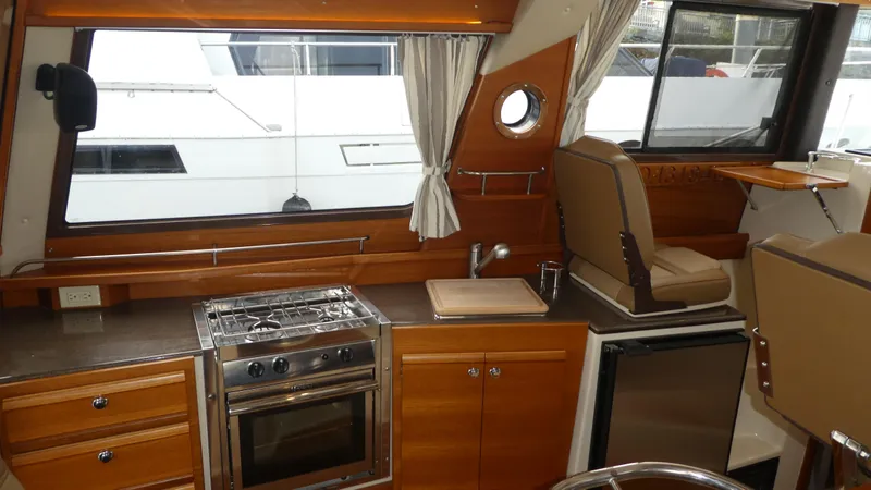 Slide: The Image of 2021 Ranger Tugs R-29 S interior with kitchen, stove, and seating area. - 26