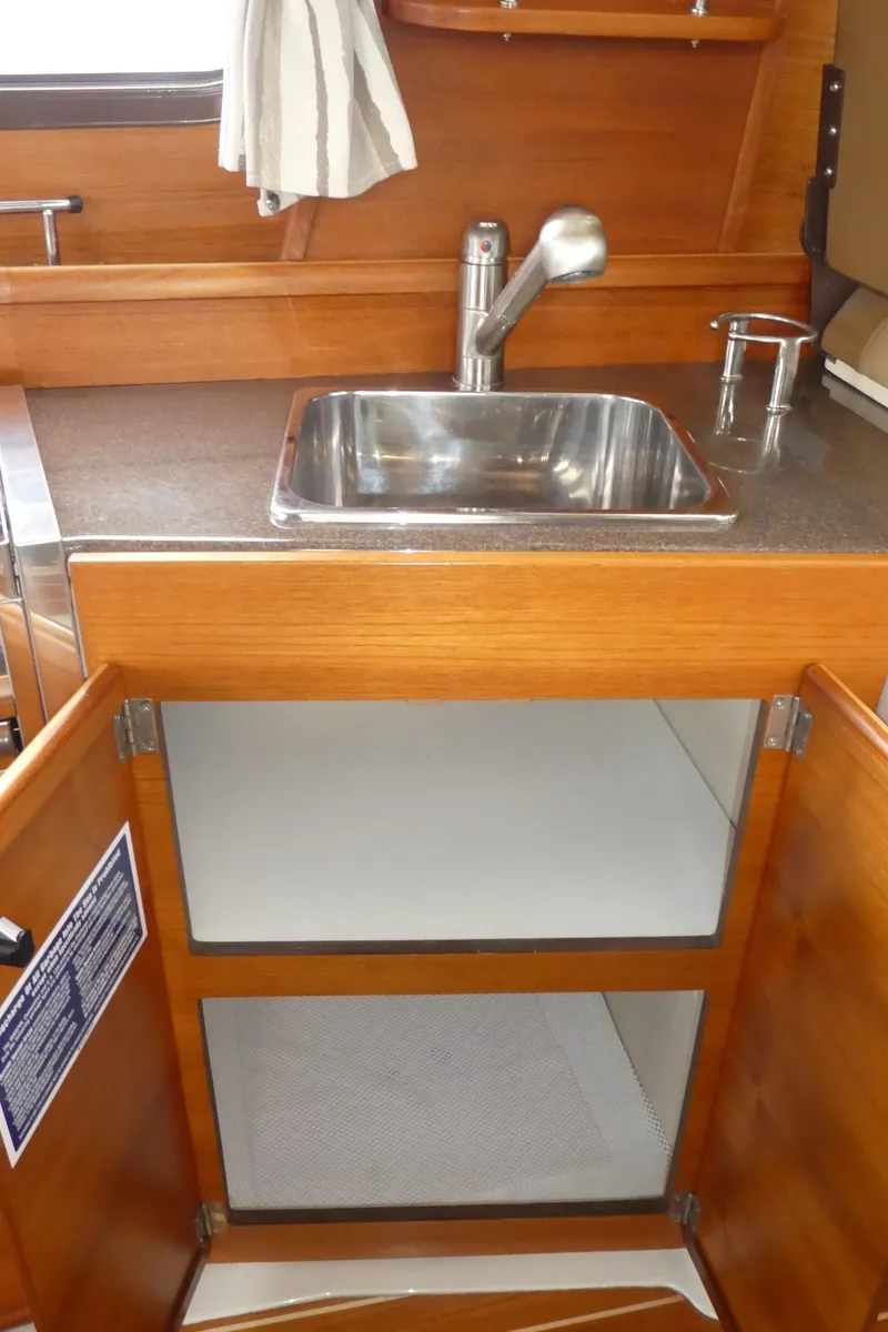 Slide: The Image of 2021 Ranger Tugs R-29 S galley sink with wooden cabinetry and open storage. - 30