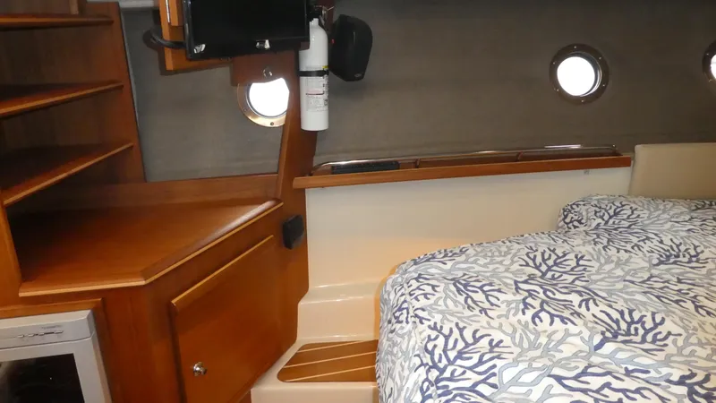 Slide: The Image of 2021 Ranger Tugs R-29 S interior cabin with bed, wooden shelves, and portholes. - 40