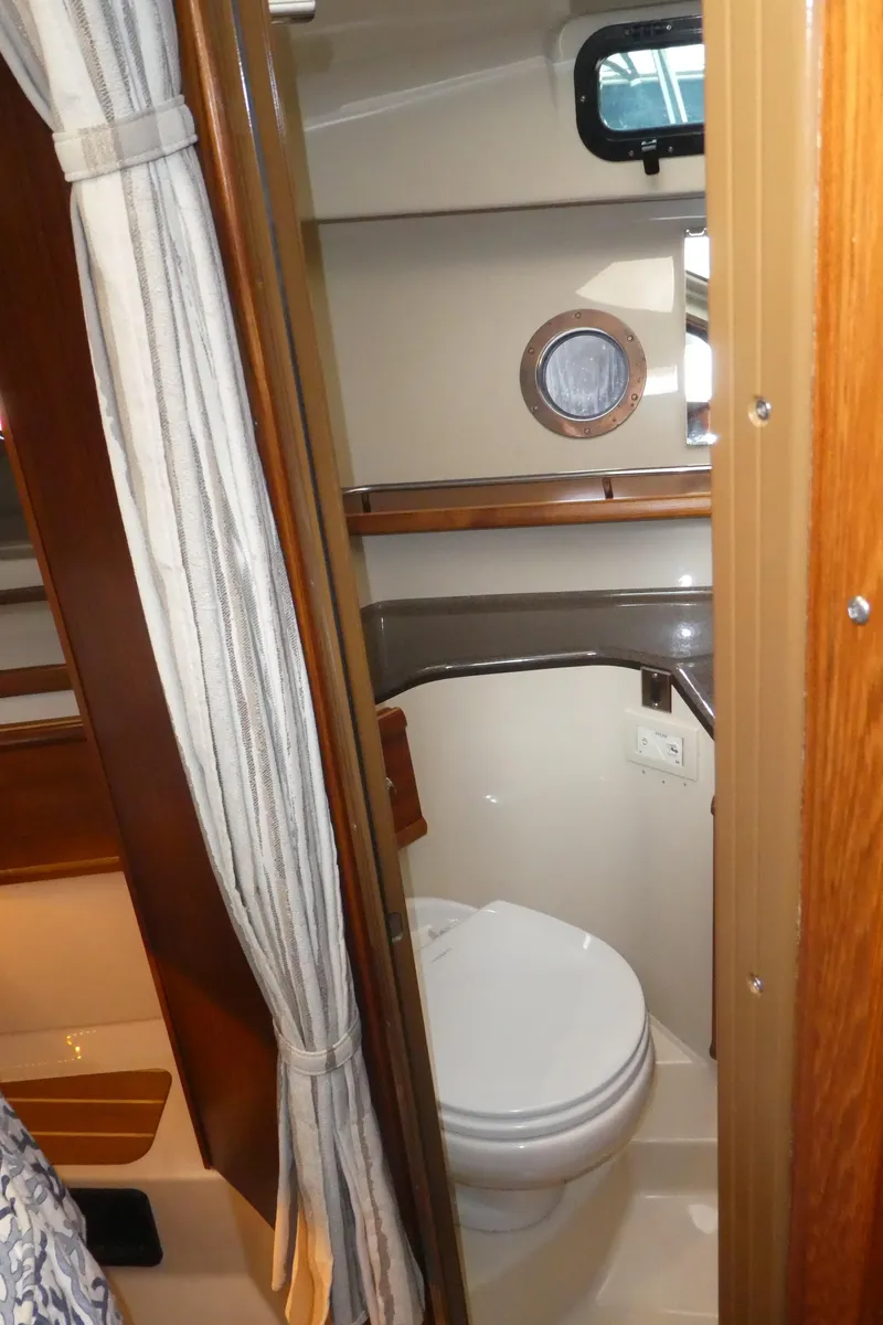Slide: The Image of 2021 Ranger Tugs R-29 S boat interior bathroom with toilet and porthole window. - 44