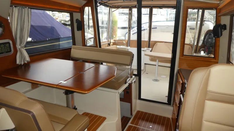Slide: The Image of 2021 Ranger Tugs R-29 S interior with dining area and seating, featuring wood accents and large windows. - 49