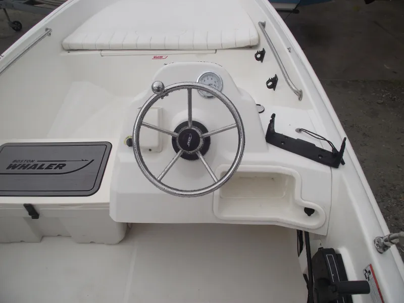 Slide: The Image of 2010 Boston Whaler 150 Super Sport boat interior with steering wheel and seating. - 13