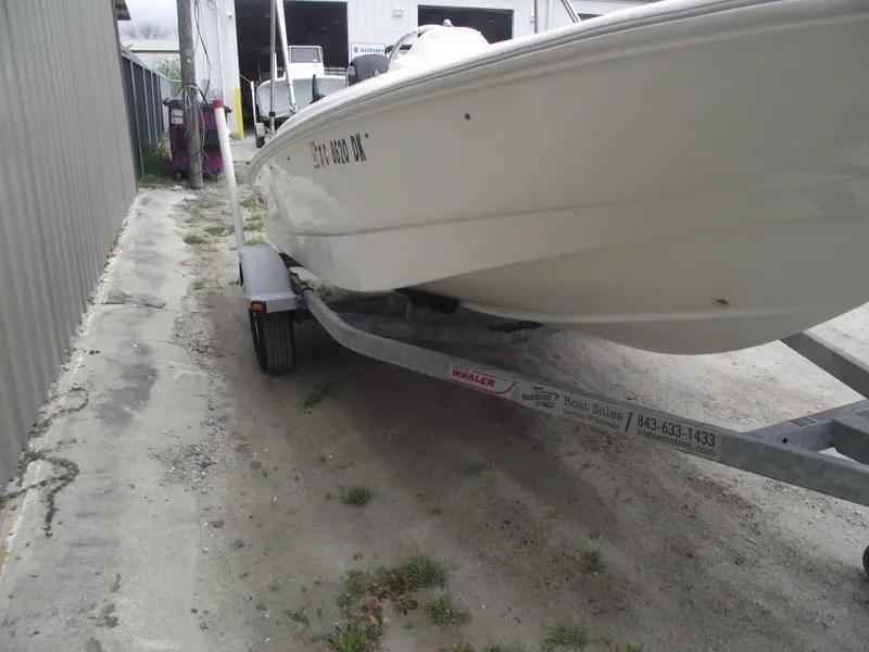 Slide: The Image of 2010 Boston Whaler 150 Super Sport on trailer, parked outdoors near a building. - 2