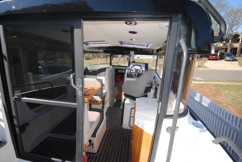 Slide: The Image of 2015 XO Boats 270 RS interior with seating and helm, docked near residential area. - 12