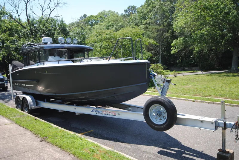Slide: The Image of 2015 XO Boats 270 RS on trailer, parked outdoors with lush greenery. - 2