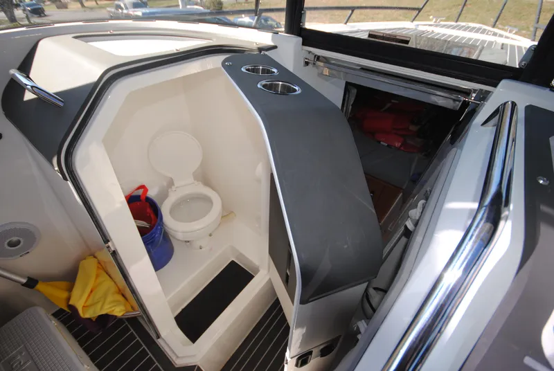 Slide: The Image of 2015 XO Boats 270 RS interior with compact marine toilet and storage area. - 23