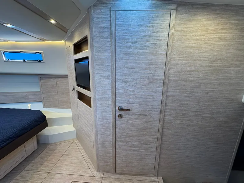 Slide: The Image of 2022 Pardo Yachts 43 interior cabin with modern design, featuring a bed, TV, and sleek wood paneling. - 19