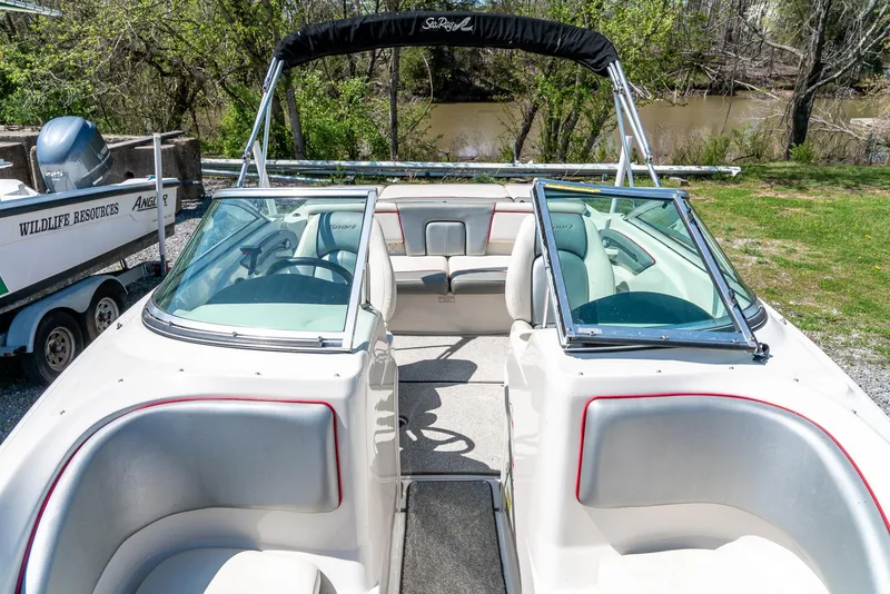 Slide: The Image of 2008 Sea Ray 205 Sport boat with open seating and canopy, parked near a river. - 23