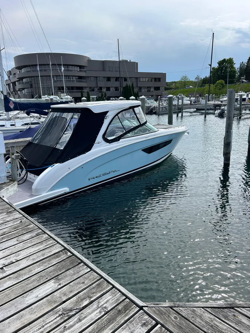 Slide: The Image of 2023 Regal 3300 boat docked at a marina with modern buildings in the background. - 1