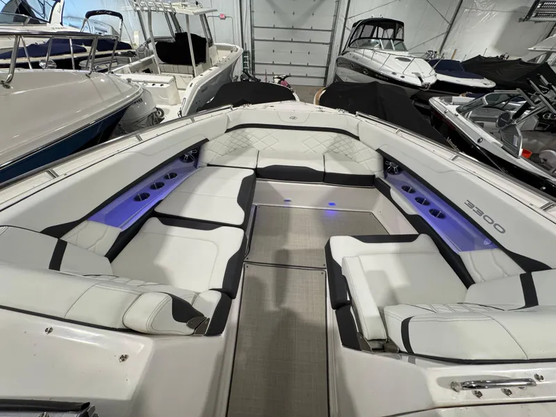 Slide: The Image of 2023 Regal 3300 boat interior with white seating and cup holders in a showroom. - 15