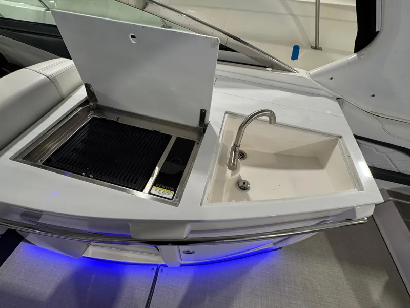 Slide: The Image of 2023 Regal 3300 boat kitchenette with grill and sink, featuring blue LED lighting. - 6