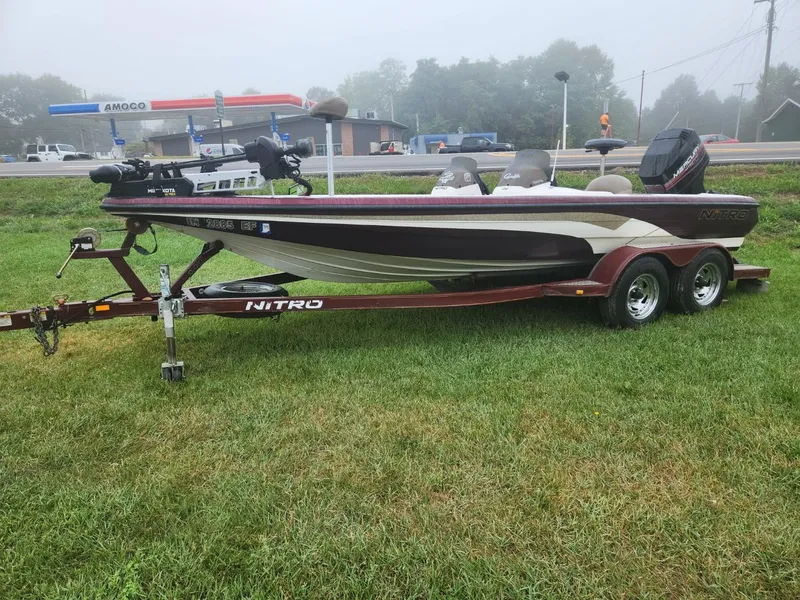 Slide: The Image of 2001 Nitro 896 DC boat on trailer, parked on grass near a road. - 1