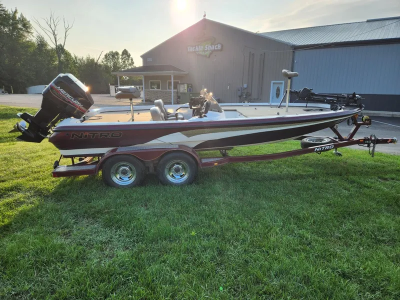 Slide: The Image of 2001 Nitro 896 DC boat on trailer, parked on grass, with building in background. - 5