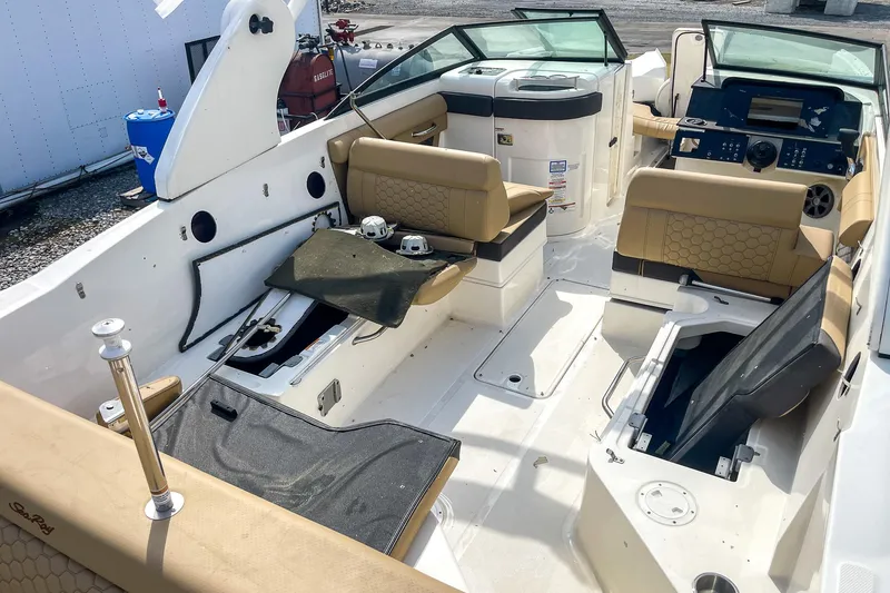 Slide: The Image of 2019 Sea Ray 270 Sundeck SDX interior with beige seating and open storage compartments. - 10