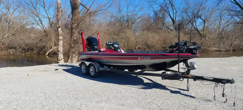 Slide: The Image of 2013 Skeeter ZX20 boat on trailer near a riverbank, surrounded by trees. - 1