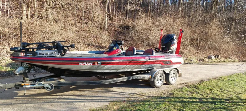 Slide: The Image of 2013 Skeeter ZX20 bass boat on trailer, parked outdoors near wooded area. - 2