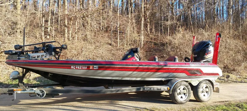 Slide: The Image of 2013 Skeeter ZX20 bass boat on trailer, parked near wooded area. - 3