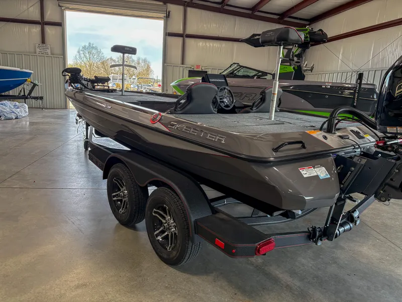 Slide: The Image of 2025 Skeeter ZXR 19 boat in showroom, featuring sleek design and dual-axle trailer. - 14