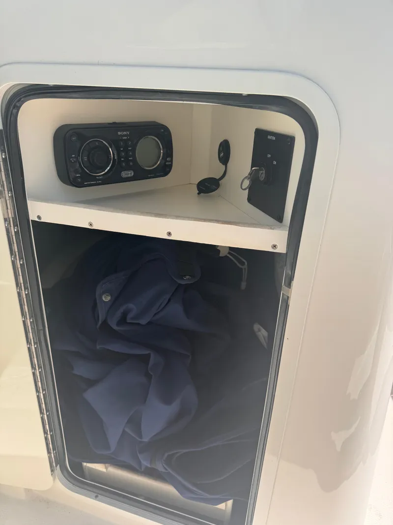 Slide: The Image of 2012 Sea Ray 200 SD storage compartment with Sony stereo and blue fabric inside. - 11