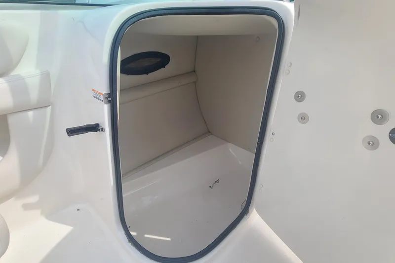 Slide: The Image of 2005 Chaparral 264 Sunesta boat storage compartment with open door, showcasing interior space. - 11