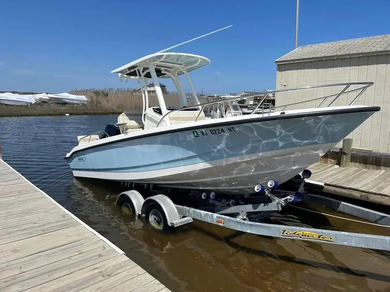 Slide: The Image of 2023 Boston Whaler 220 Dauntless boat on trailer at dockside under clear blue sky. - 1