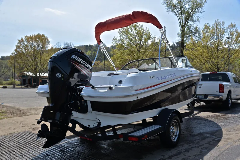 Slide: The Image of 2018 Tahoe 550 TS boat on trailer with Mercury outboard motor, parked near trees. - 14