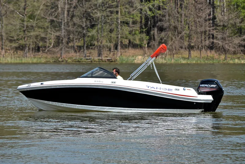 Slide: The Image of 2018 Tahoe 550 TS boat cruising on a calm lake with trees in the background. - 9