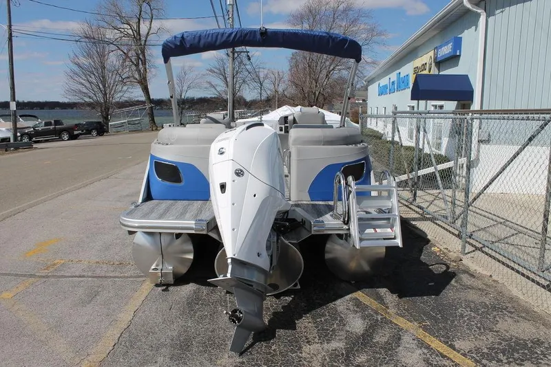 Slide: The Image of 2025 Bennington L Quad Bench 25 LFB pontoon boat with outboard motor, docked on pavement. - 3