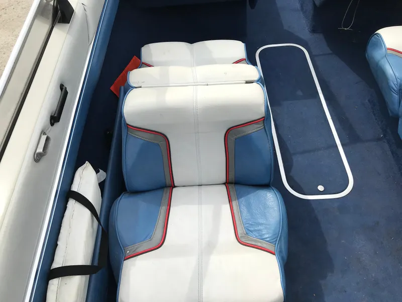Slide: The Image of 1987 Bayliner 1950 Capri boat interior with blue and white seating, red accents, and carpeted floor. - 11