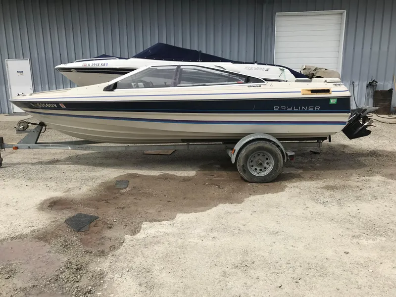 Slide: The Image of 1987 Bayliner 1950 Capri boat on trailer, parked outdoors near a building. - 23