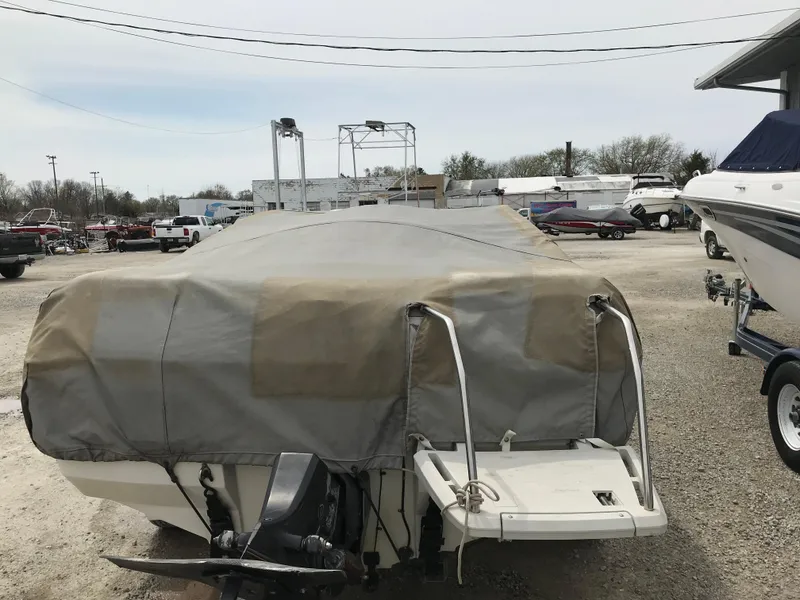 Slide: The Image of 1987 Bayliner 1950 Capri boat covered, parked in a lot with other boats. - 28